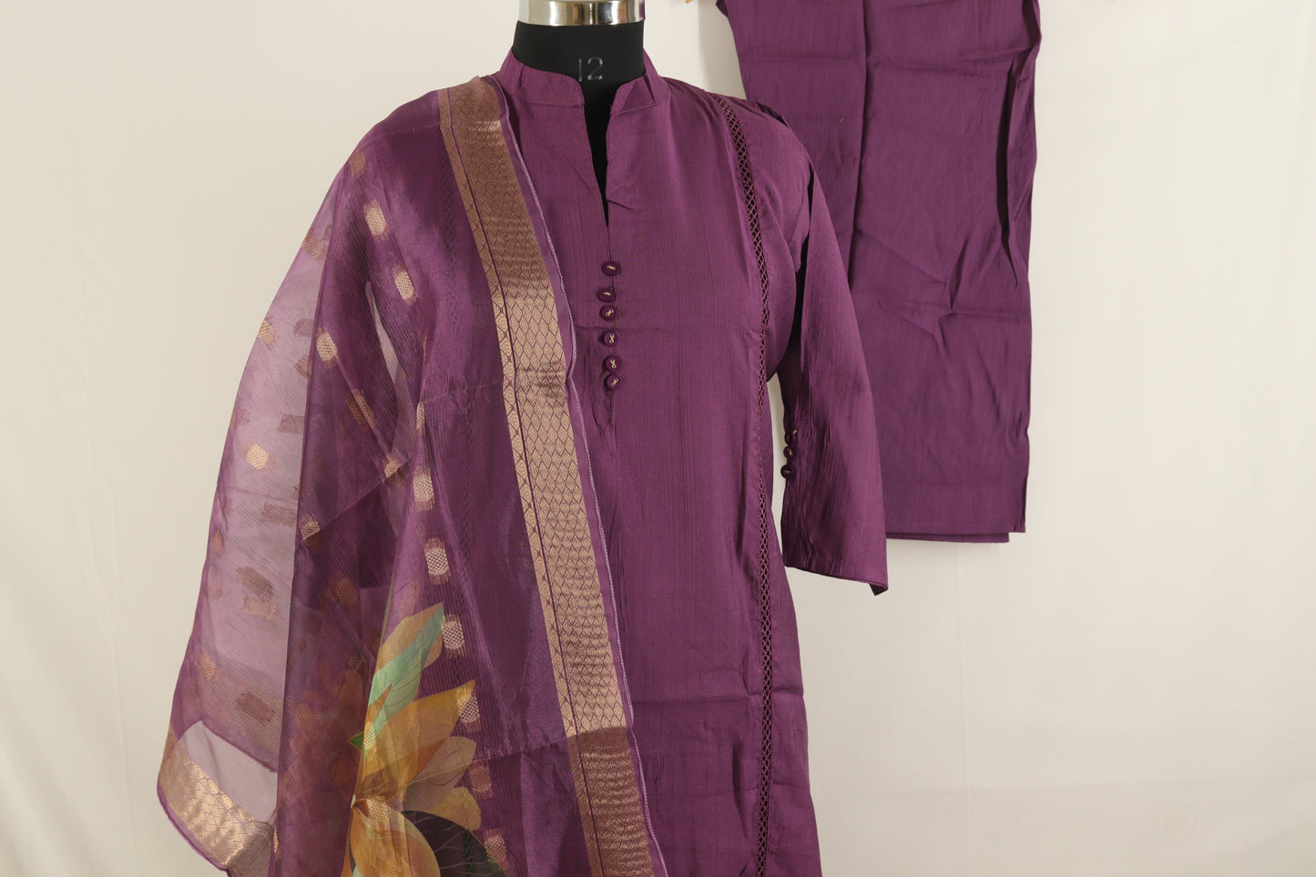 Purple traditional outfit with a floral shawl on a mannequin against a plain background