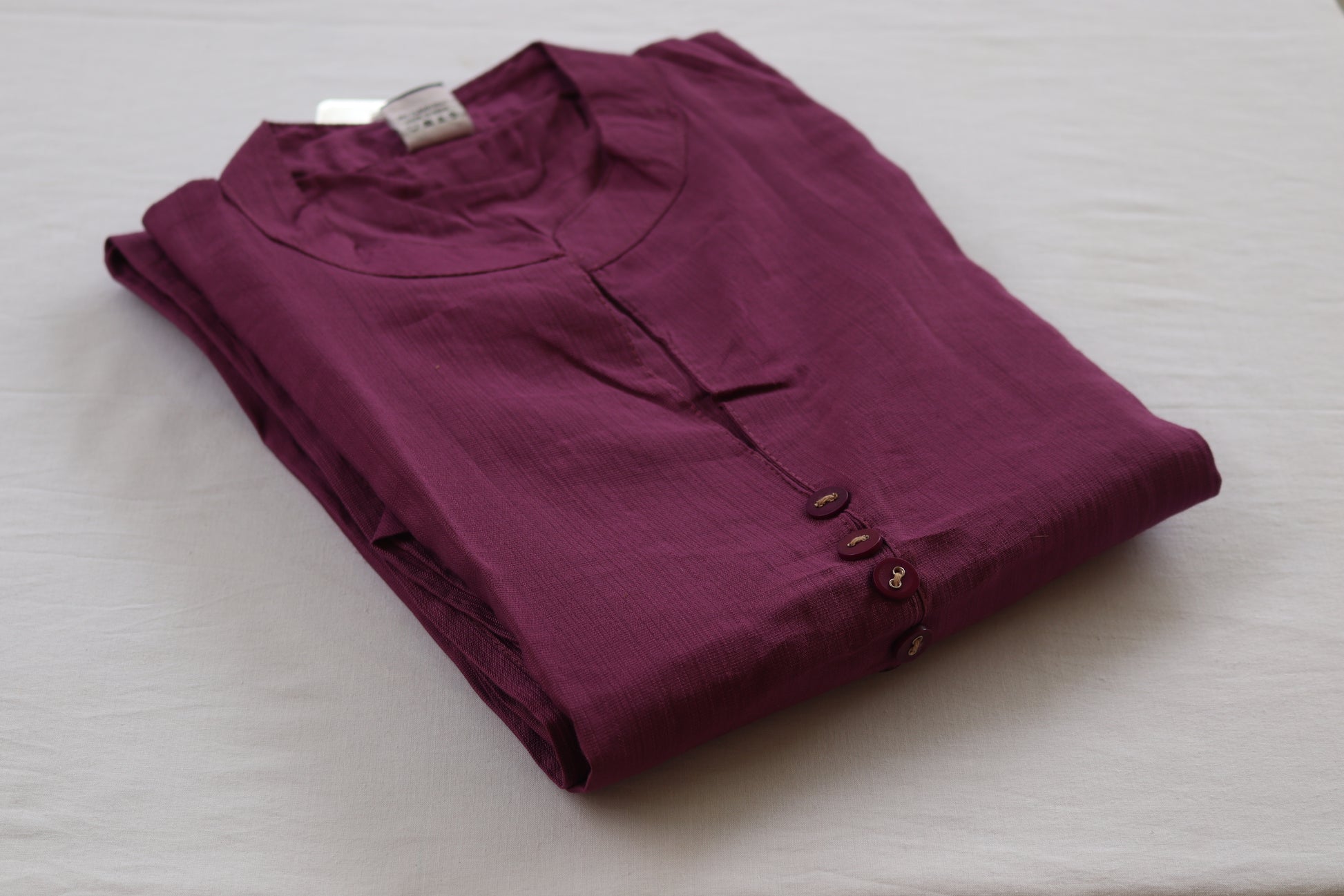 Folded purple shirt on a white surface