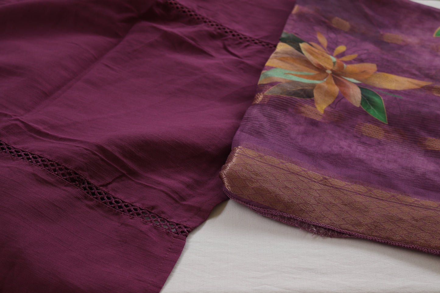 Close-up of a purple fabric with floral embroidery on a white surface